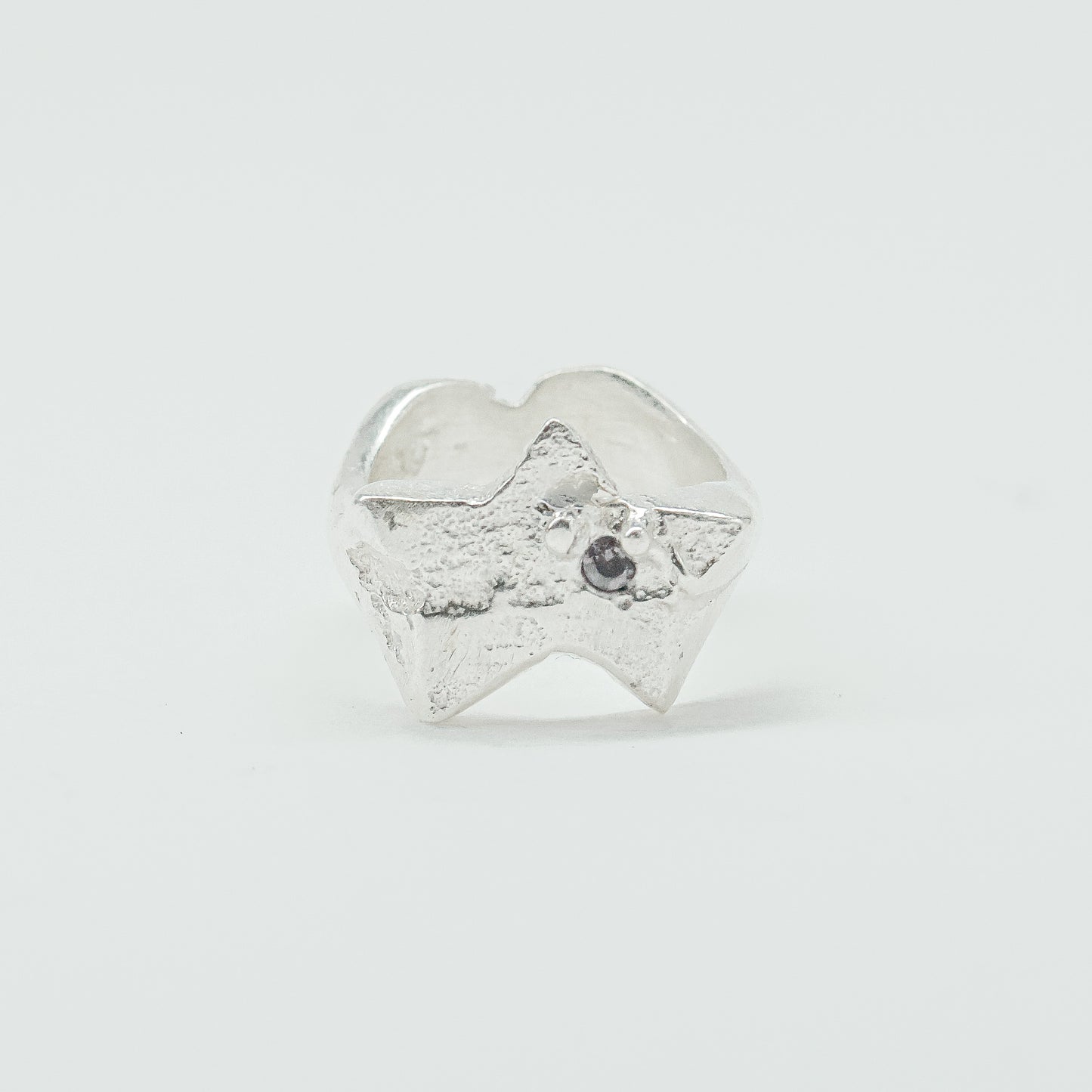 Sculptural silver ring showcasing both a heart and star form, with small gemstones set into each motif. Handmade and one of a kind.
