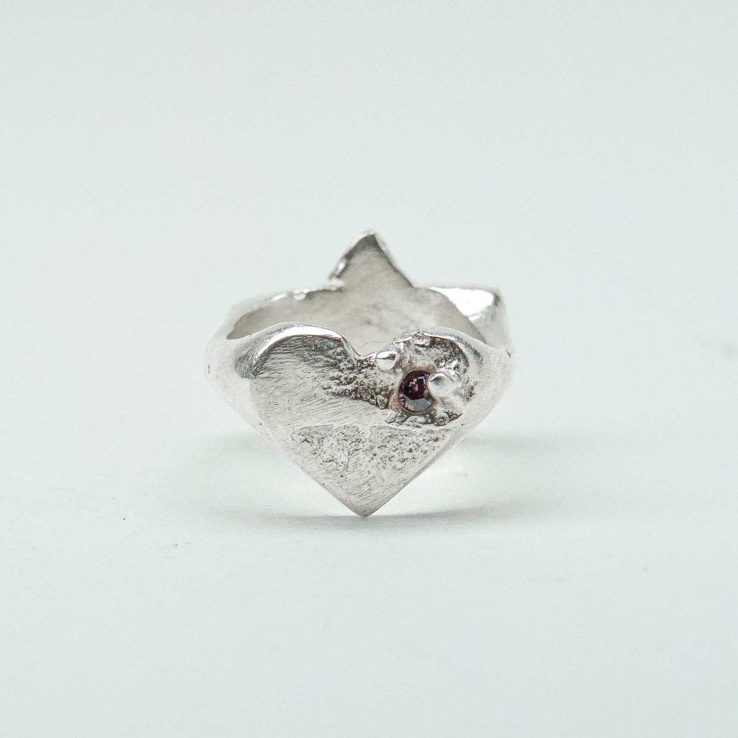 Sculptural silver ring showcasing both a heart and star form, with small gemstones set into each motif. Handmade and one of a kind.