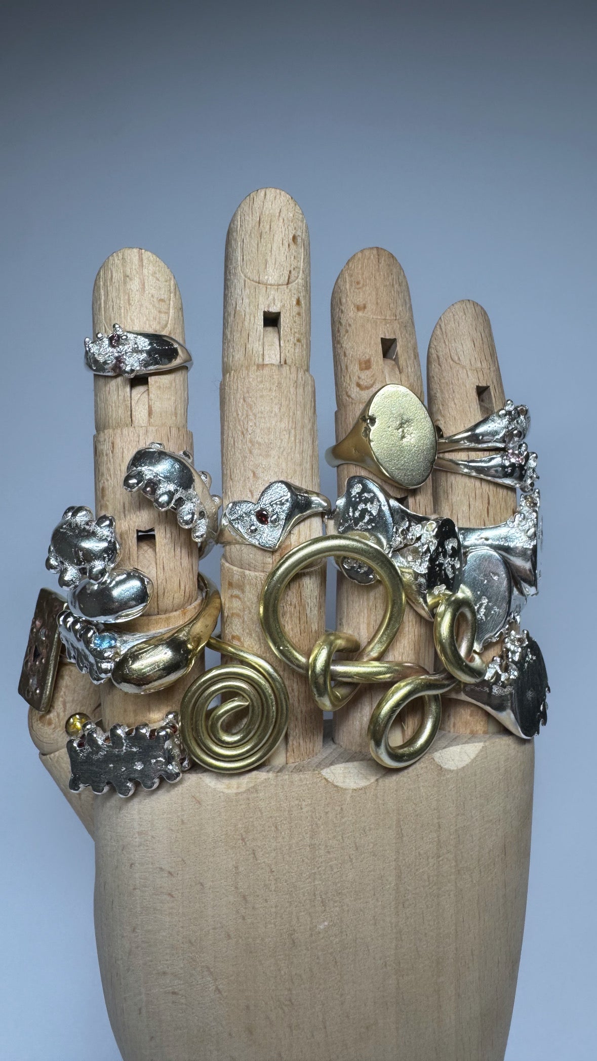 Mannequin hand wearing multiple rings with various designs on a plain background