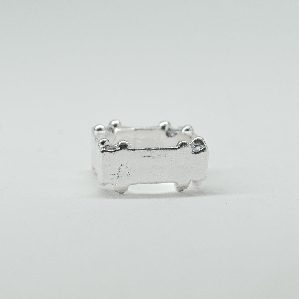 Hand-sculpted sterling silver ring with a bold, square silhouette and deep textured finish, featuring small round gemstones set into each corner.