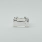 Hand-sculpted sterling silver ring with a bold, square silhouette and deep textured finish, featuring small round gemstones set into each corner.