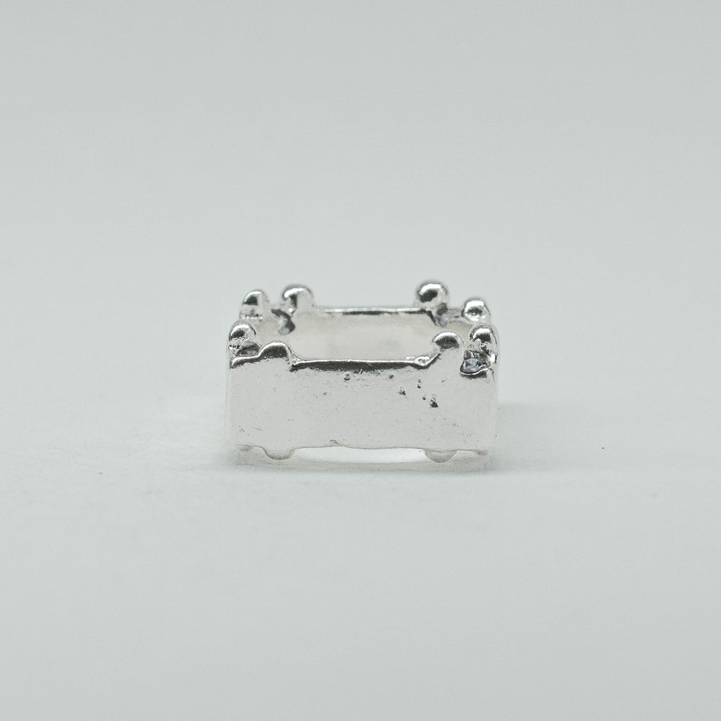 Hand-sculpted sterling silver ring with a bold, square silhouette and deep textured finish, featuring small round gemstones set into each corner.
