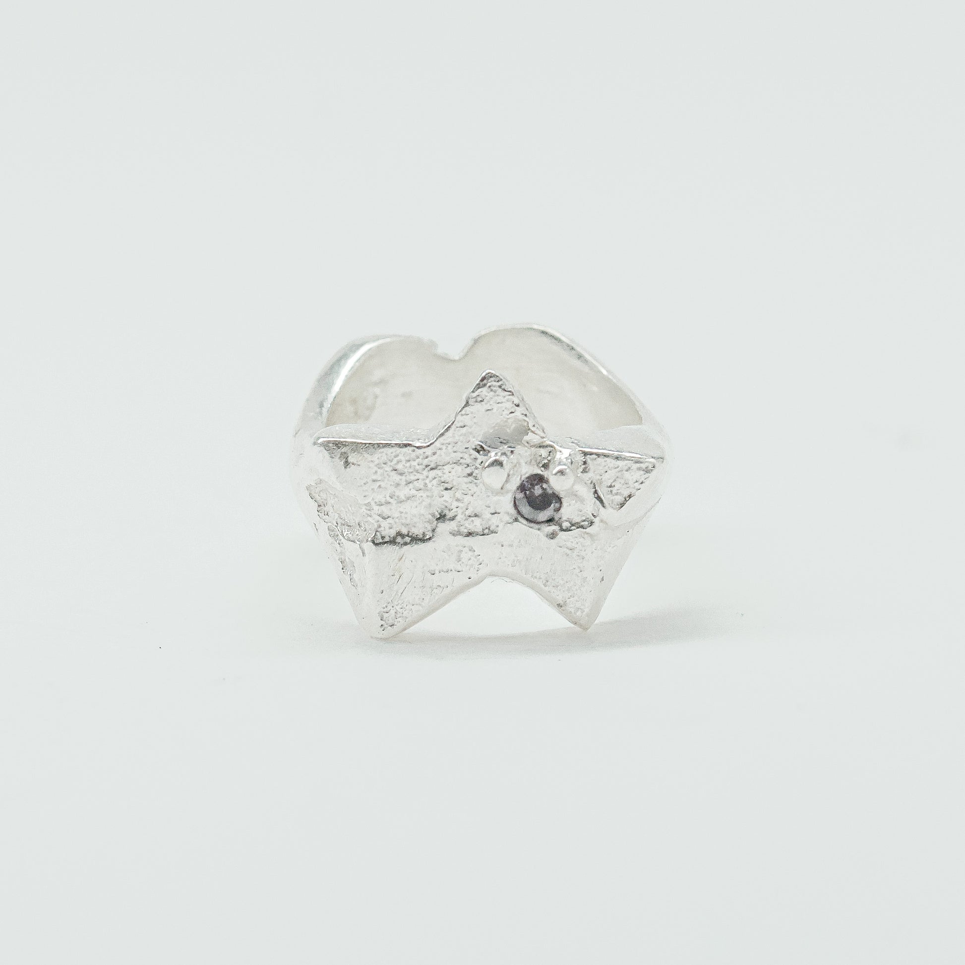 Sculptural silver ring showcasing both a heart and star form, with small gemstones set into each motif. Handmade and one of a kind.