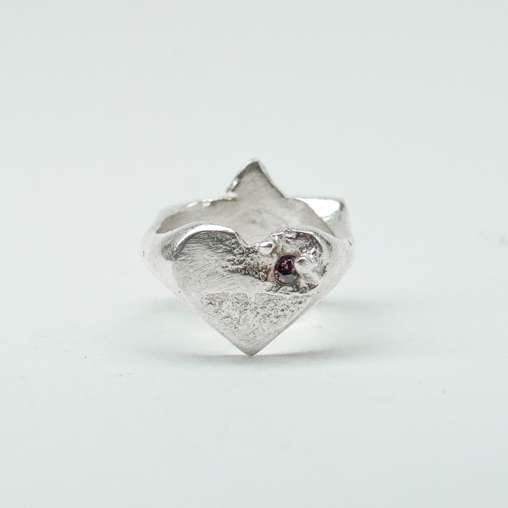 Sculptural silver ring showcasing both a heart and star form, with small gemstones set into each motif. Handmade and one of a kind.
