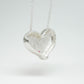 Bulbous heart-shaped sterling silver pendant, hand-sculpted with drilled textures and encrusted with small scattered gemstones. Playful and raw, with a cartoon-like silhouette.
